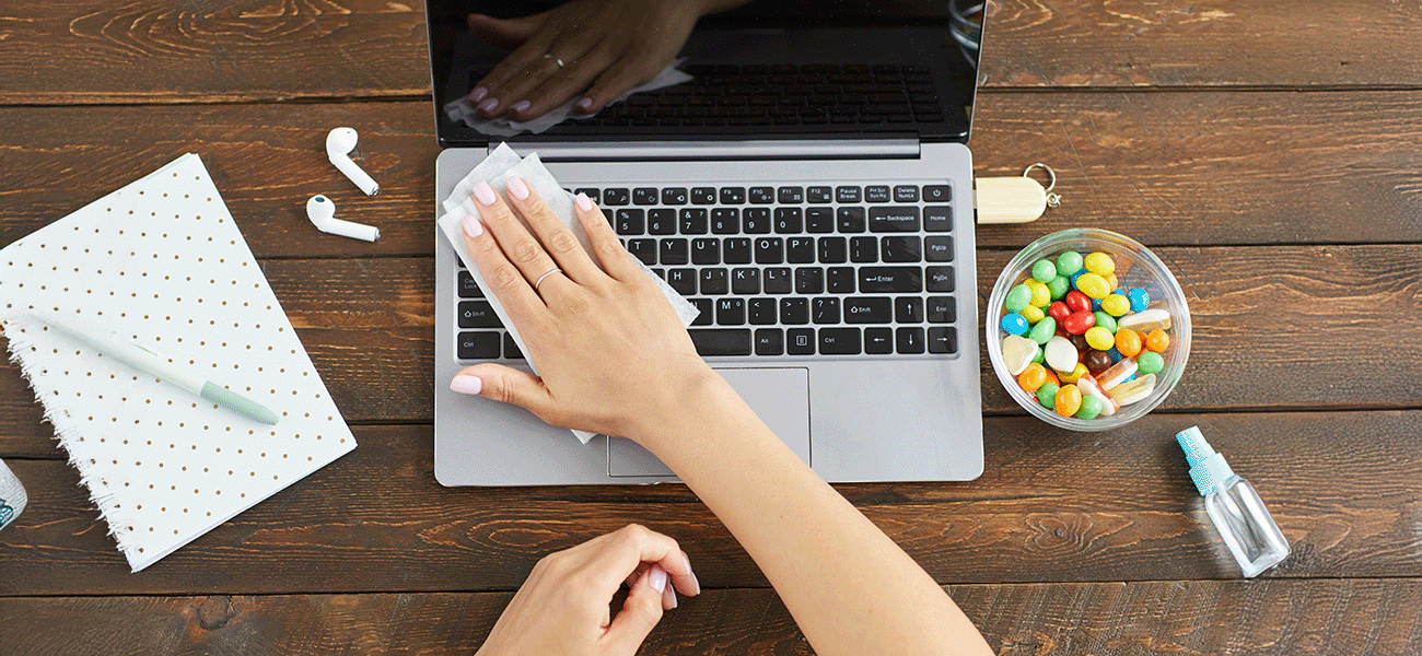 A hand cleaning a laptop keyboard.