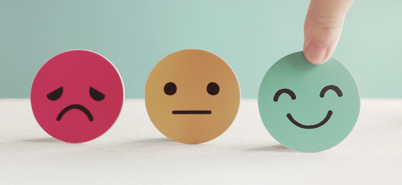 Three smiley faces; one sad face in red, one neutral face in yellow, and one happy face in green.