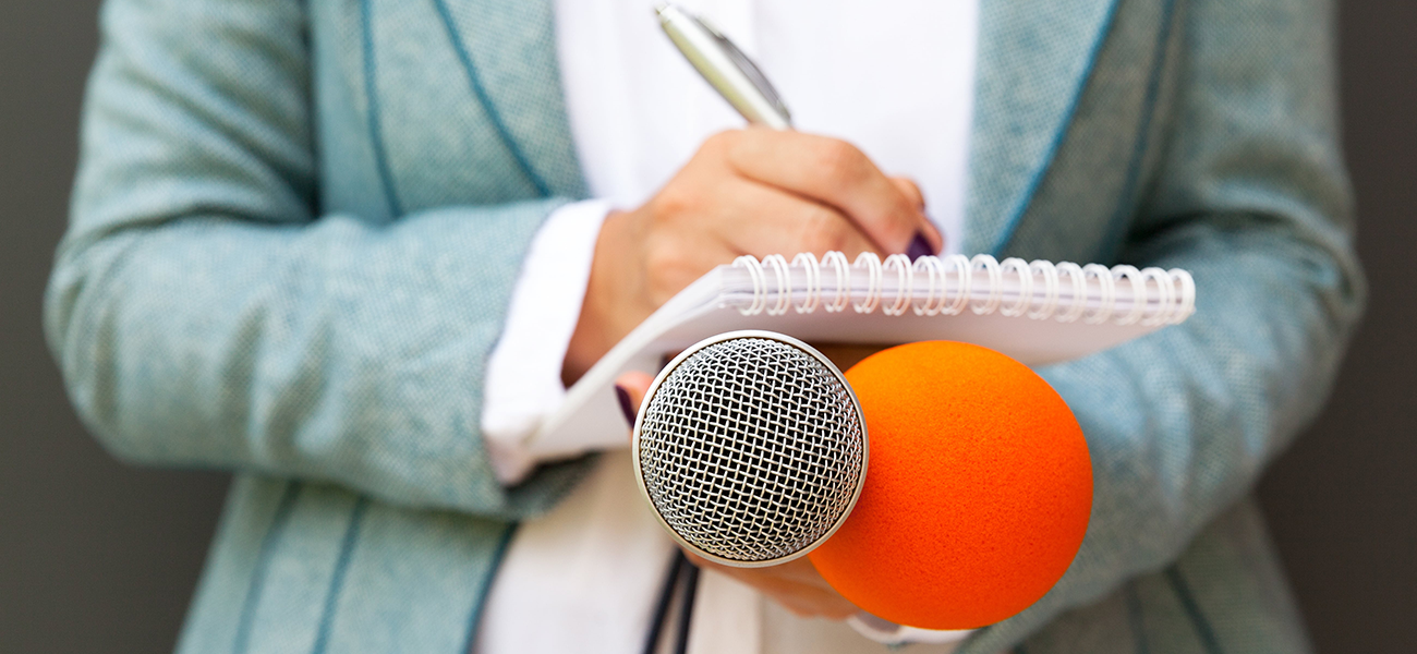 An interviewer holding a mic and a notepad.
